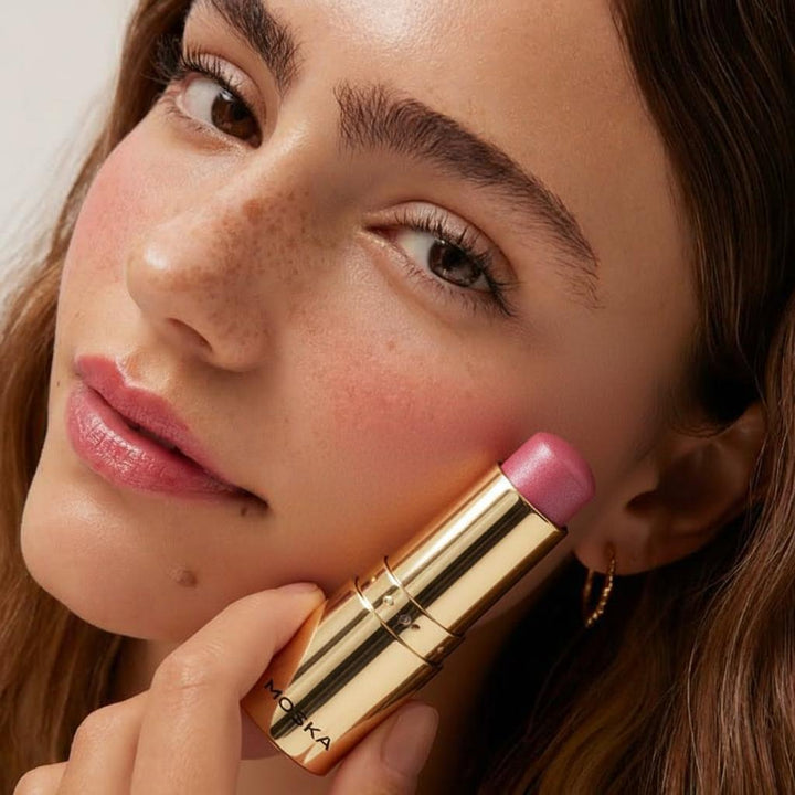 Close-up of a woman holding a pink lipstick with a brand name.